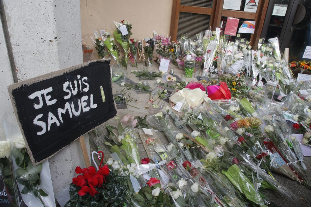 Πινακίδα που αναγράφει "Είμαι ο Samuel" και λουλούδια στο πάτωμα έξω από το σχολείο όπου δούλευε ο Γάλλος καθηγητής.