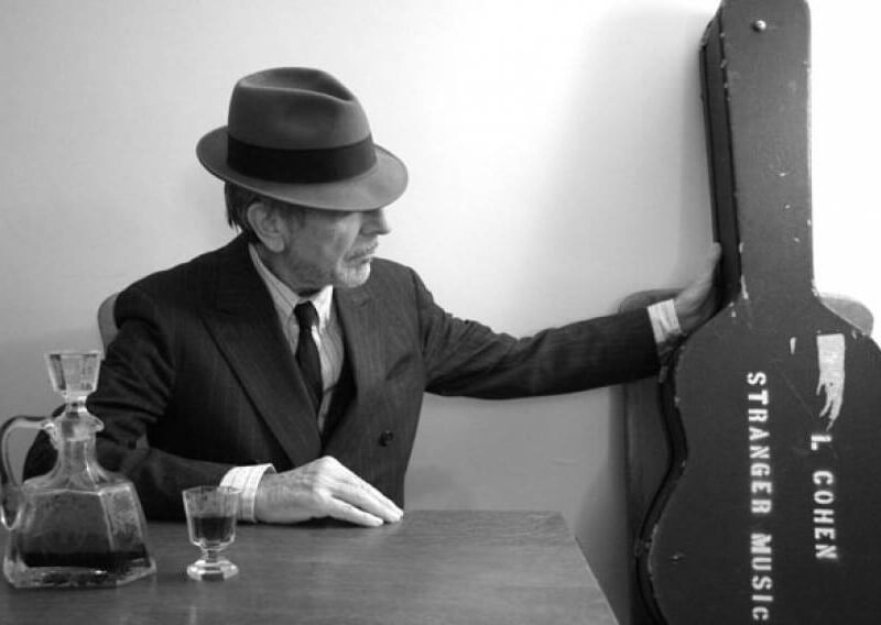 Φωτογραφία του Leonard Cohen, όπου στην θήκη της κιθάρας του γράφει "L. Cohen - Strangere Music".