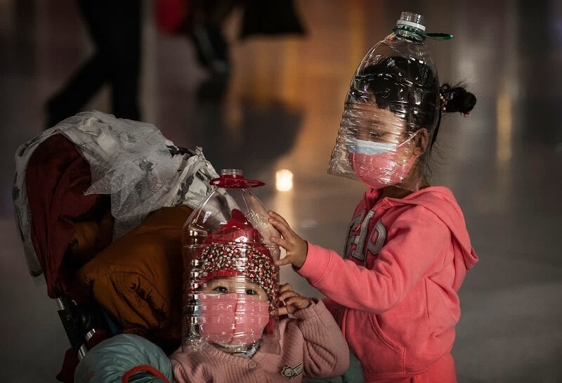 30 Ιανουαρίου - Παιδιά φορούν πλαστικά μπουκάλια ως προσωρινές μάσκες, ενώ περιμένουν να κάνουν check in σε μια πτήση στο αεροδρόμιο του Πεκίνου.