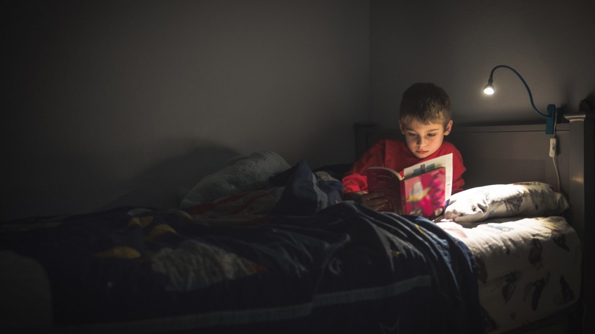 Boy reading in his bed at night.
